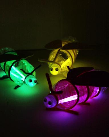 Three fireflies makes with glowsticks and bottles. One is green, another is yellow, and the last one in purple.