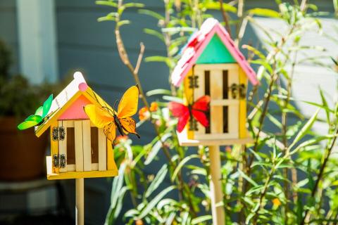 Two painted butterfly houses in a garden.