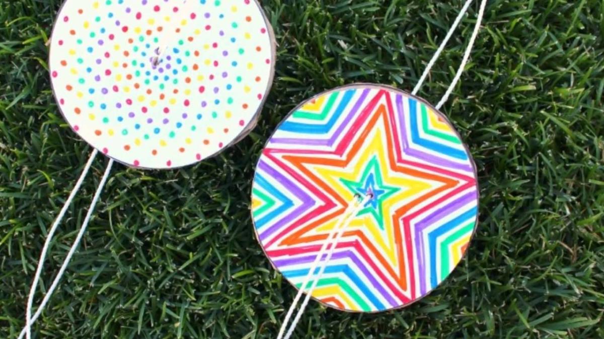 Two paper spinners, one covered in rainbow dots, the other in rainbow streaks.