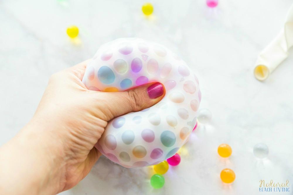 A person squeezing a stress ball made from a balloon and water beads